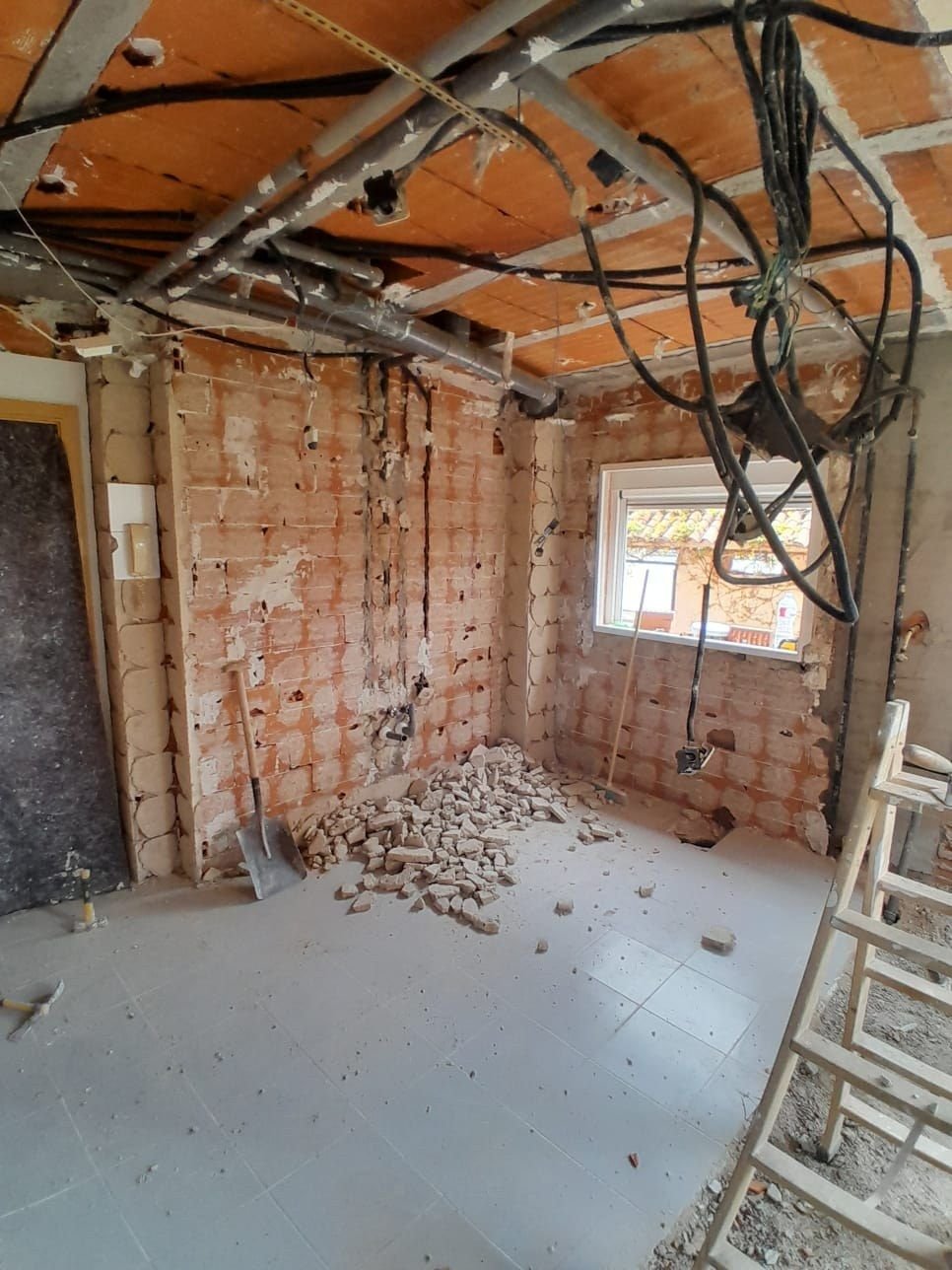 Cocina en demolición: ladrillo con rozas y cableado antiguo colgando